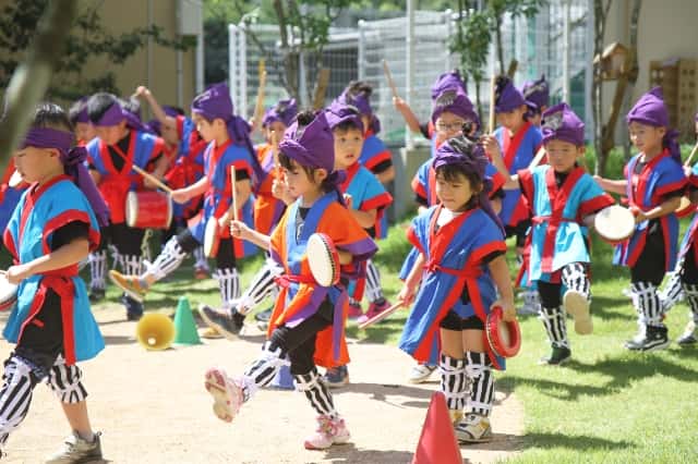 園児達が野外でエイサー衣装を着て歩いている写真