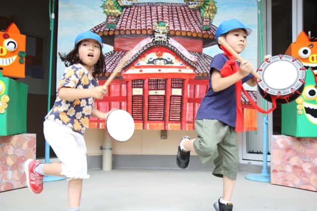 男の子と女の子がそれぞれ太鼓を持って片足を上げている写真