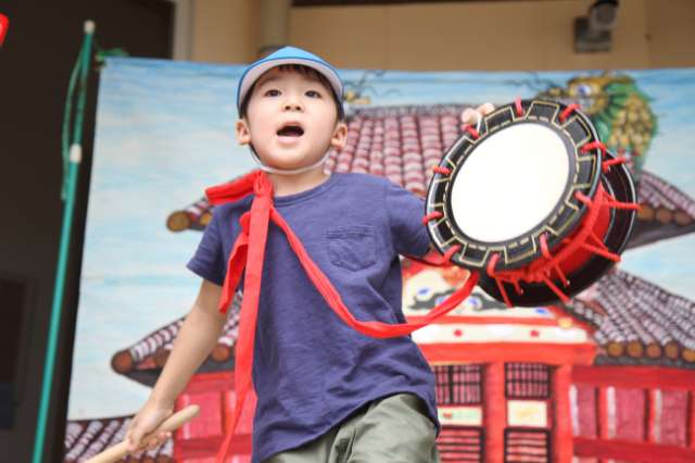 男の子が左手に太鼓を持って口を大きく開けている写真