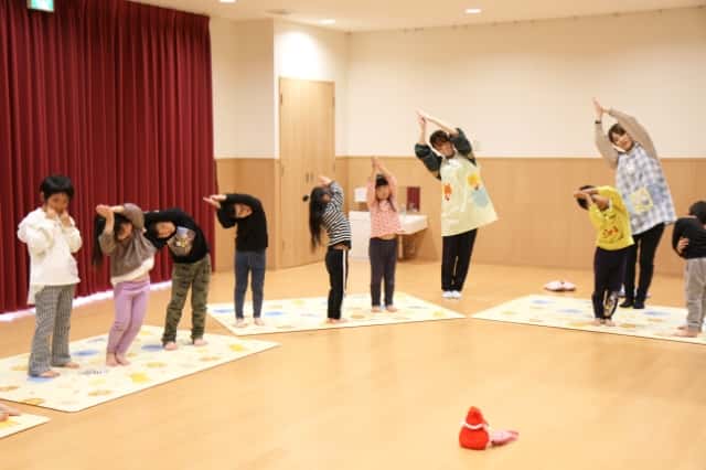 先生と園児達が両手を頭の上で合わせて体を斜めにしている写真