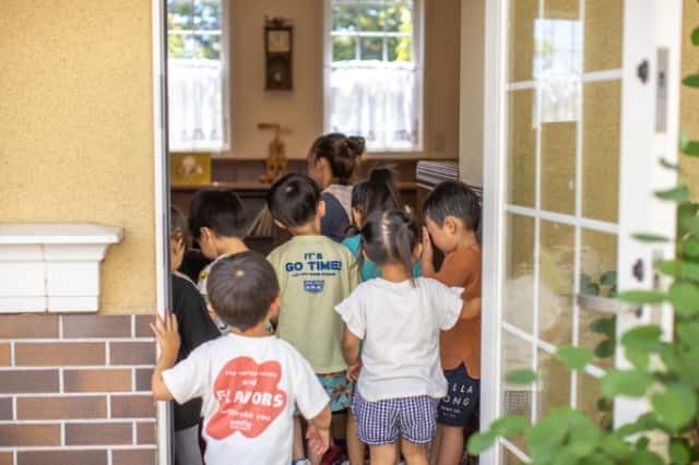 扉から園児達がえほんのおうちの中に入っていく写真